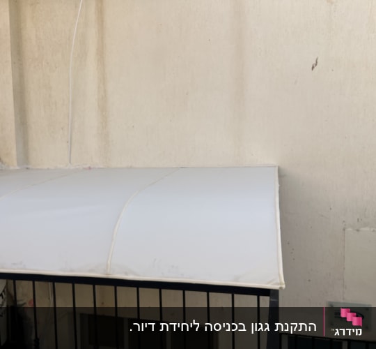 סוכך לבן מותקן על קיר חיצוני